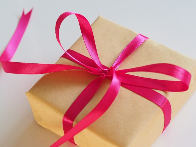 Eine braune Geschenkbox mit einer rosa Schleife darum gebunden.