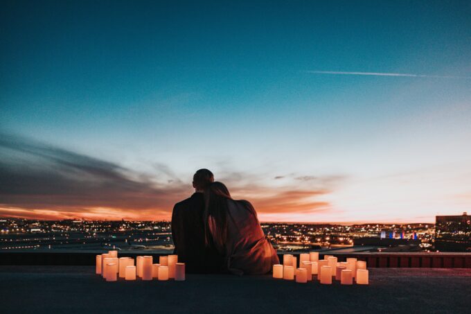Ein Paar sitzt auf einem Felsvorsprung mit Kerzen vor sich.