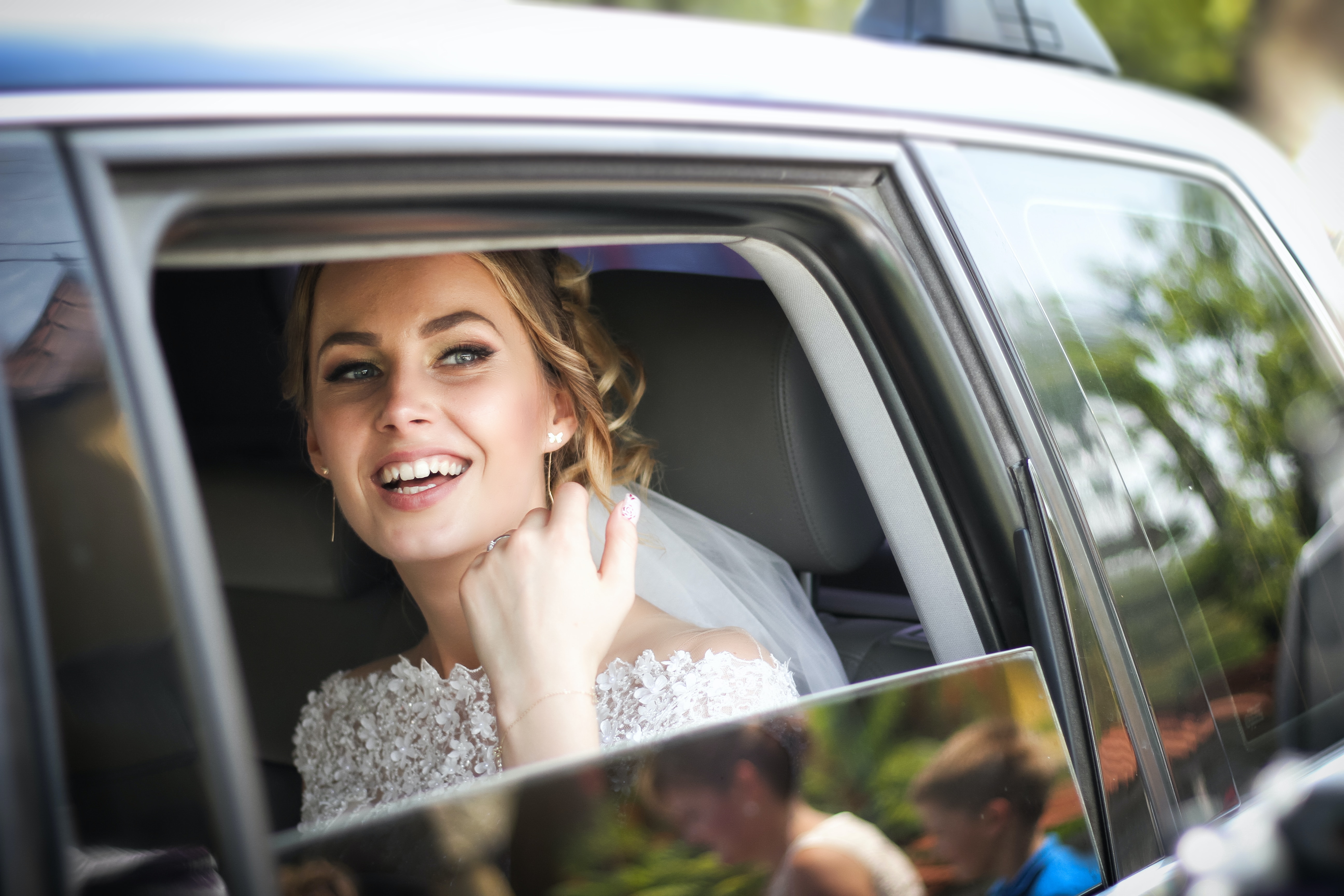 Eine Braut sitzt auf dem Rücksitz eines Autos.