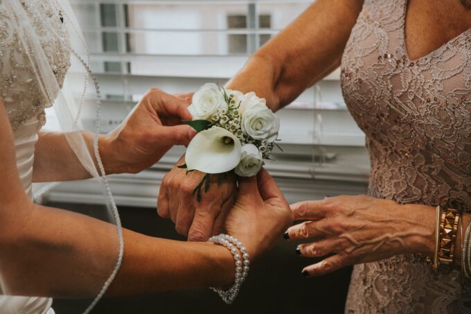 Eine Frau zieht die Corsage einer Braut an.
