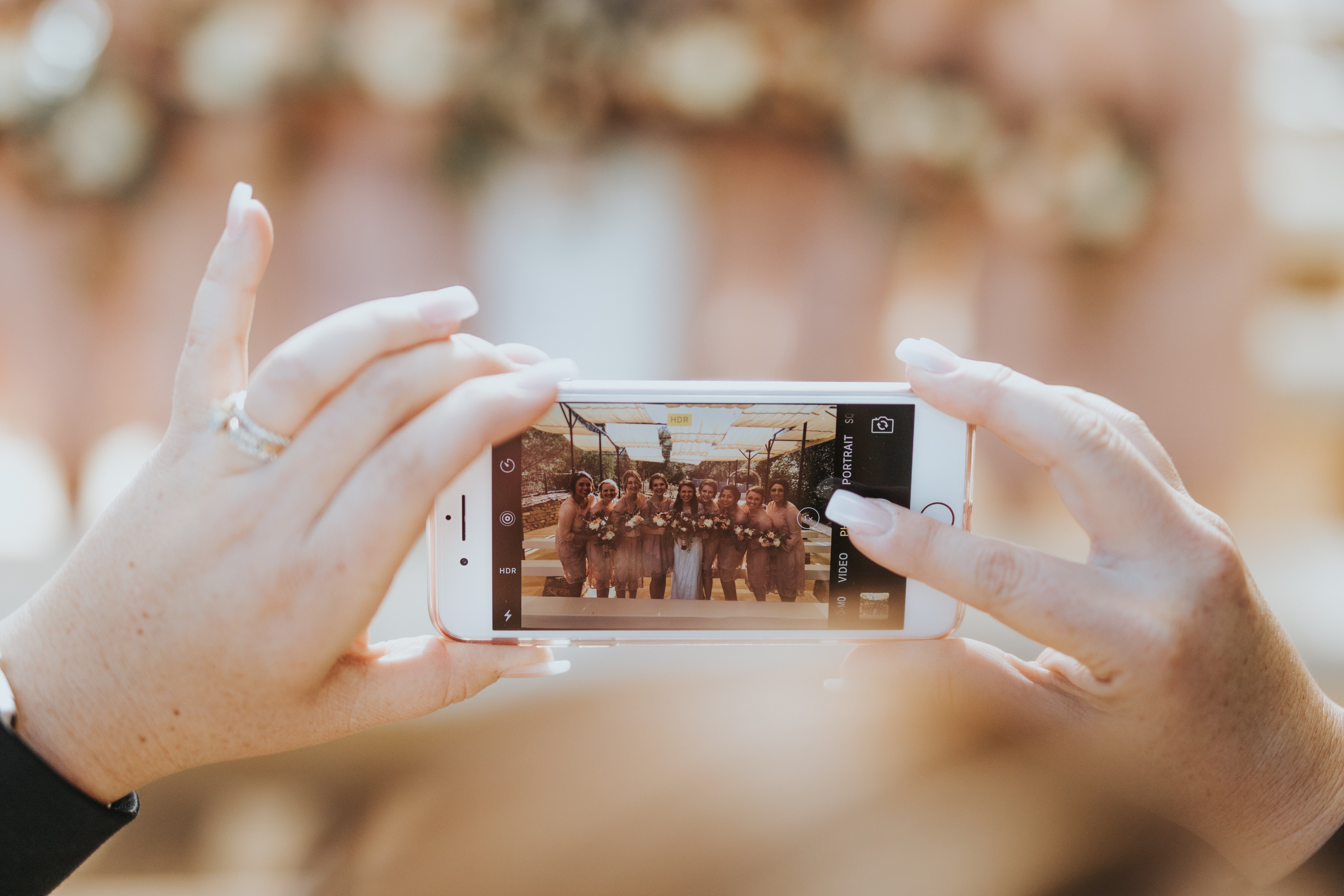Eine Frau macht mit ihrem Handy ein Foto von ihrer Hochzeitsfeier.