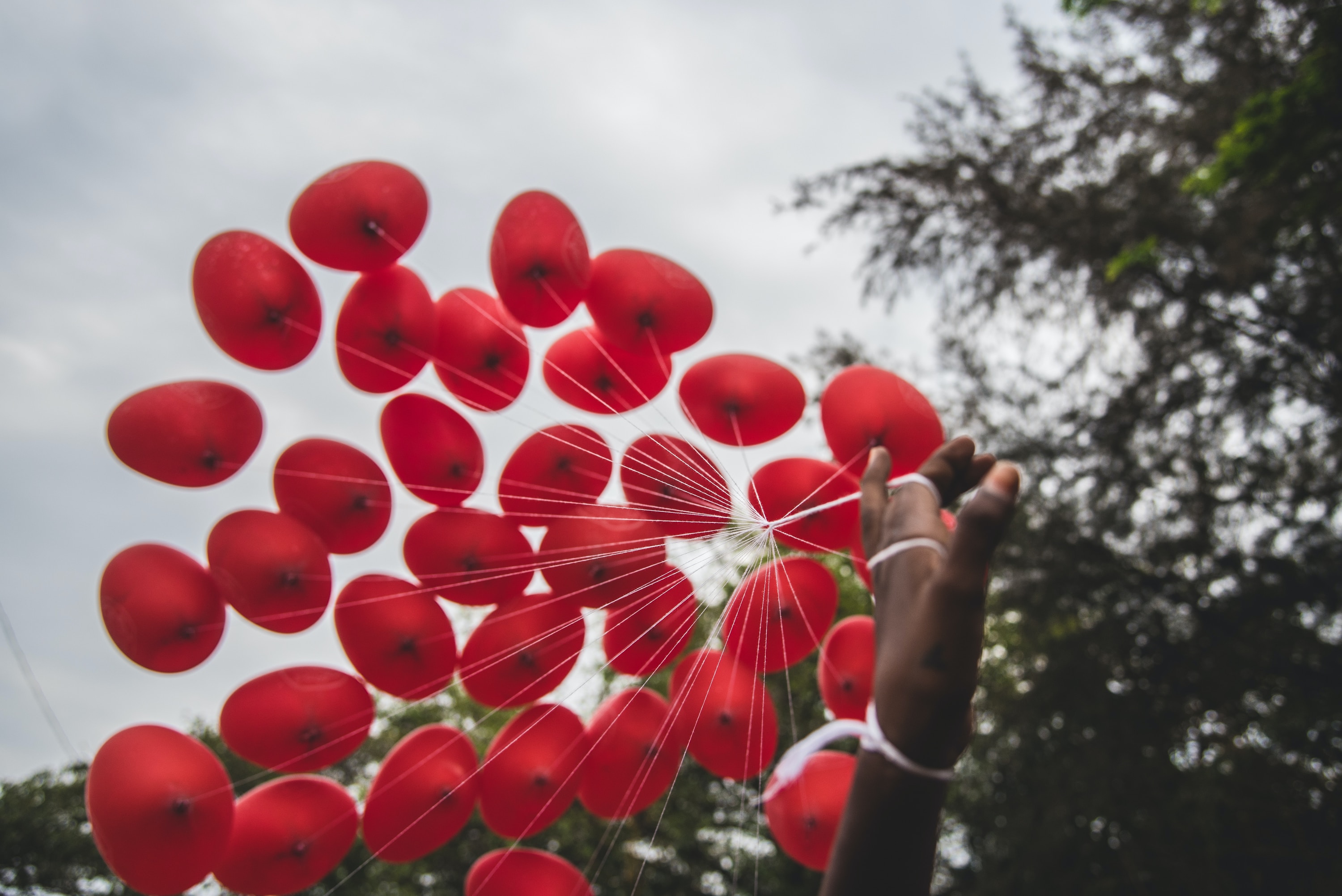 Eine Person hält einen Haufen roter Luftballons in der Hand.