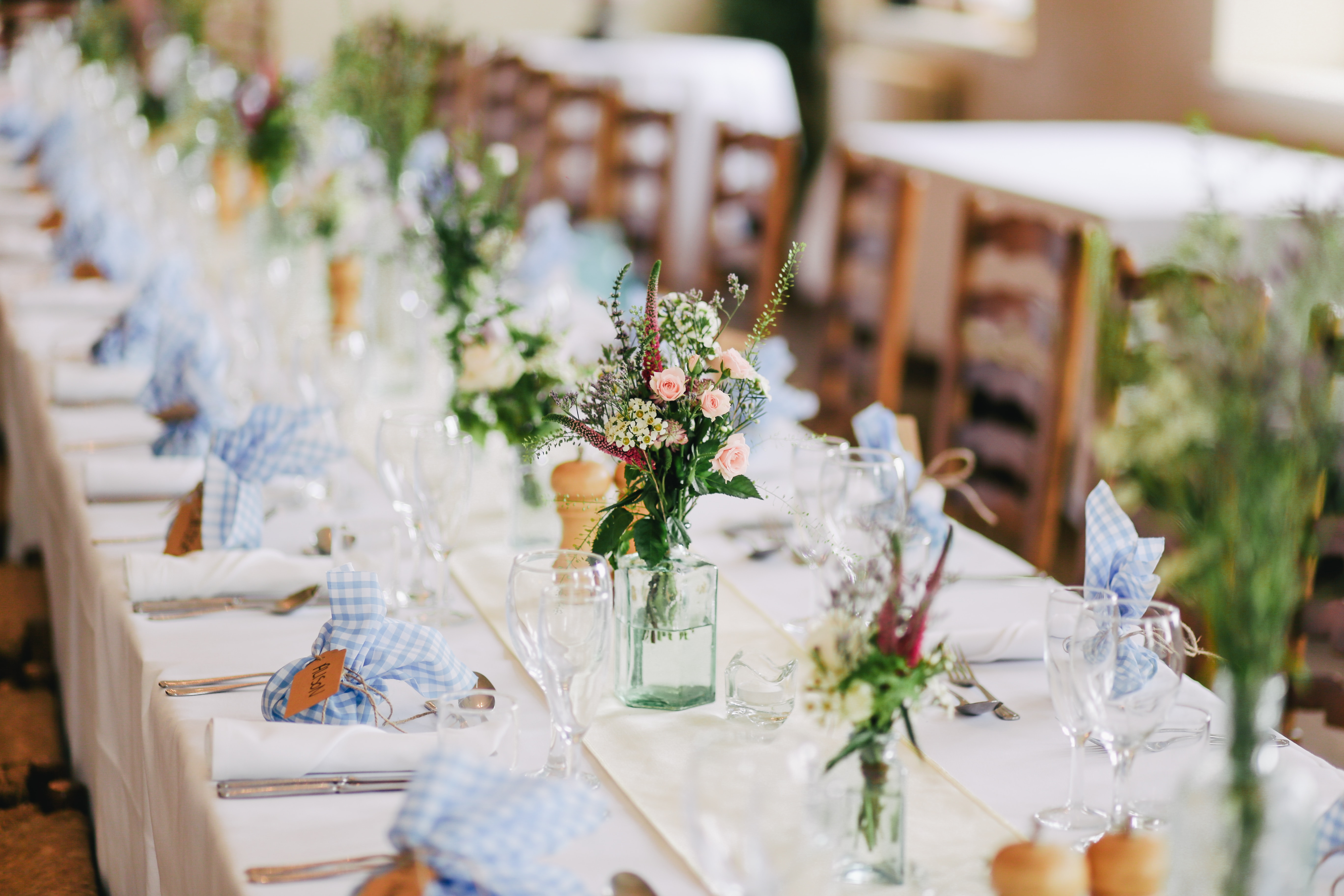 Ein langer Tisch mit blauen und weißen Servietten und Vasen.