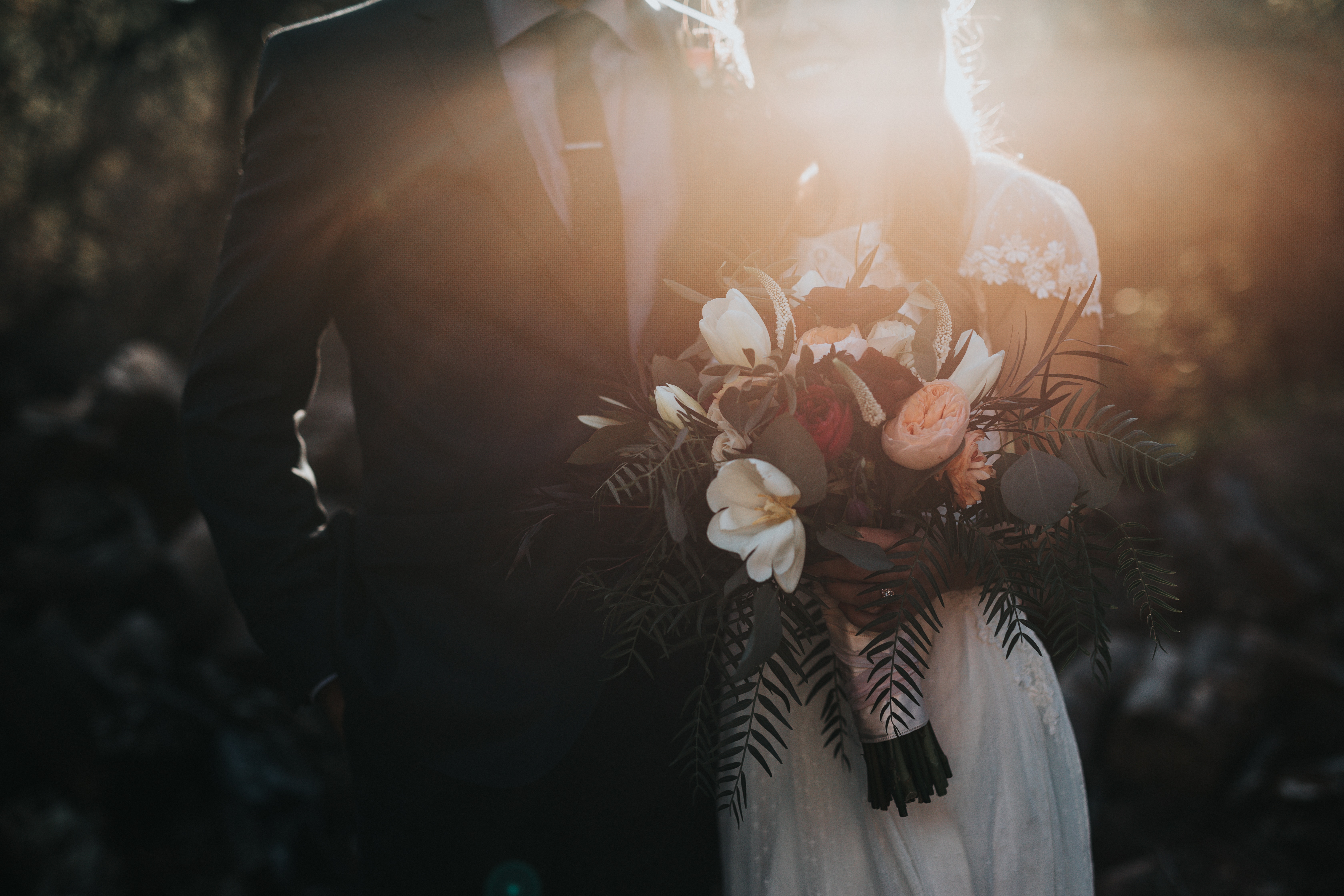 Eine Braut und ein Bräutigam stehen vor der Sonne.