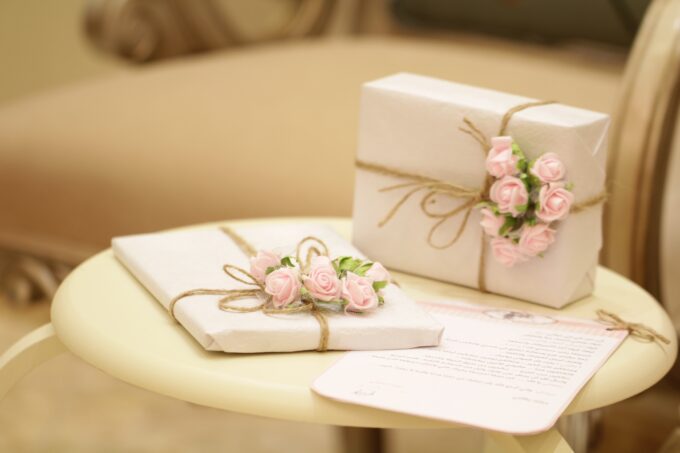 Zwei Geschenkboxen mit rosa Rosen auf einem Tisch.