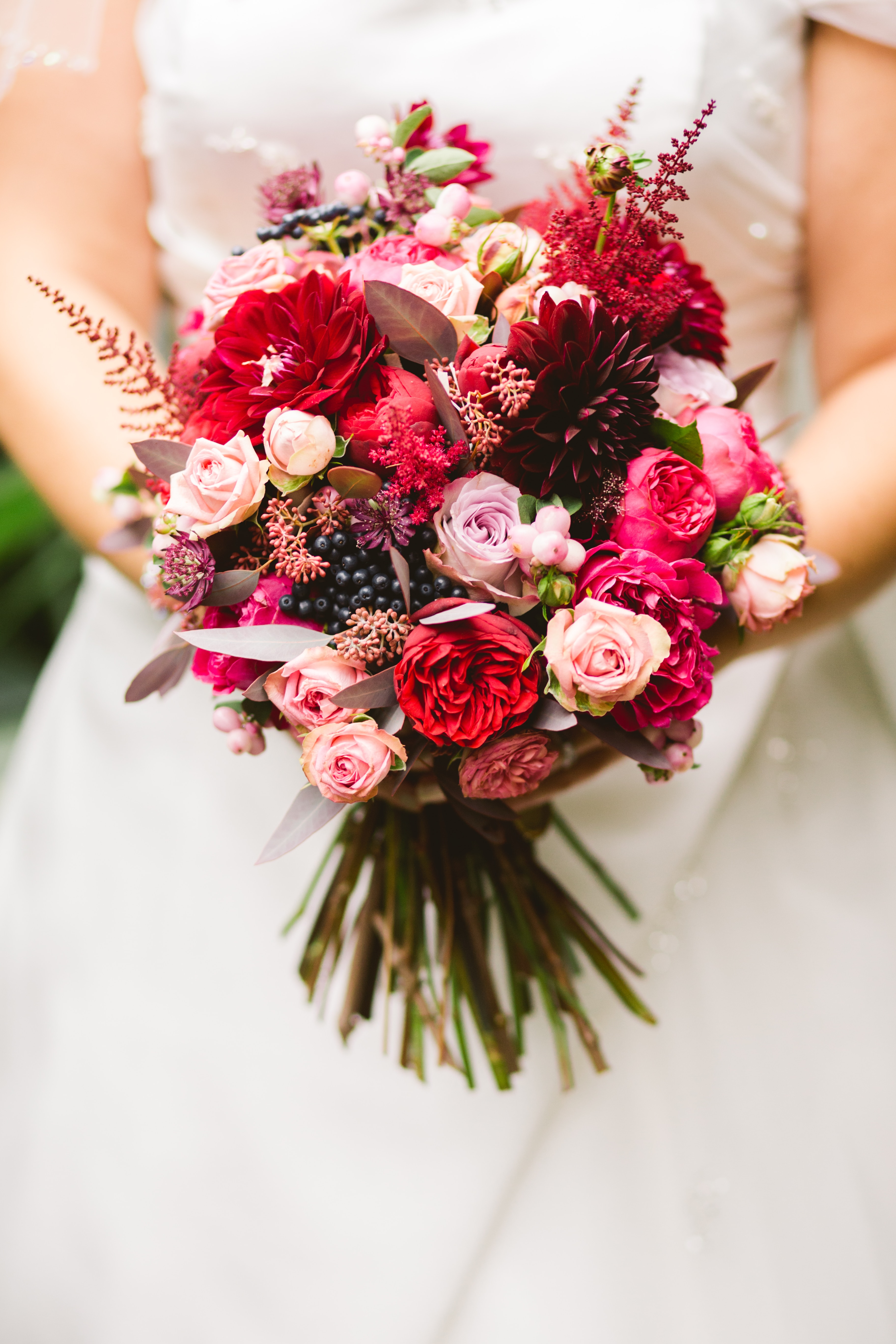 Eine Braut hält einen Strauß roter und rosa Blumen.