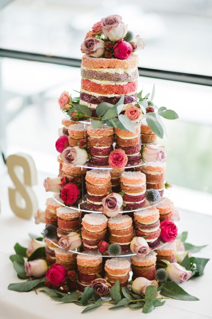 Eine mehrstufige Torte, dekoriert mit Blumen und Cupcakes.