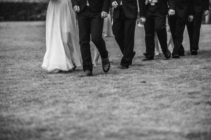 Ein Schwarz-Weiß-Foto einer Hochzeitsgesellschaft, die gemeinsam spazieren geht.