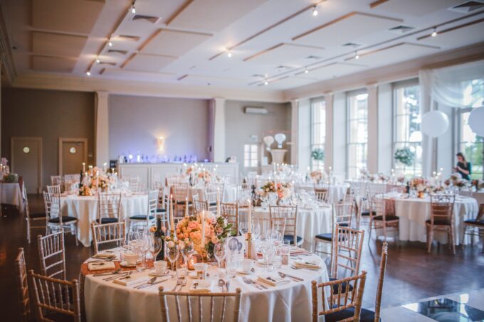 Eine Hochzeitsfeier in einem großen Raum mit weißen Tischen und Stühlen.