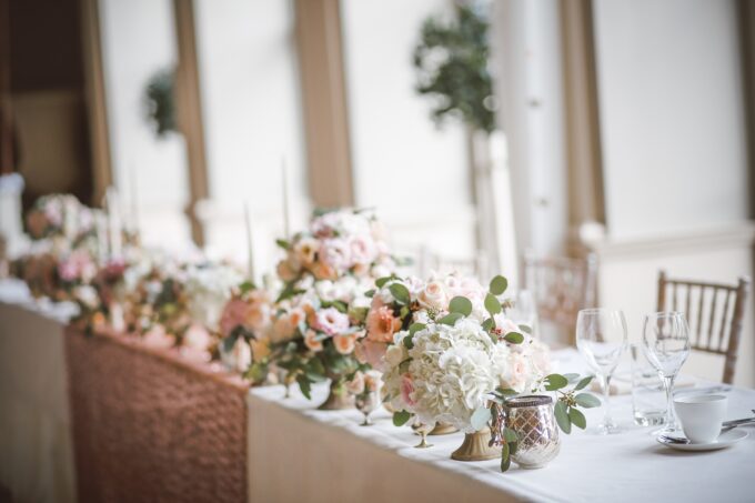 Ein langer Tisch mit Blumen und Kerzen darauf.