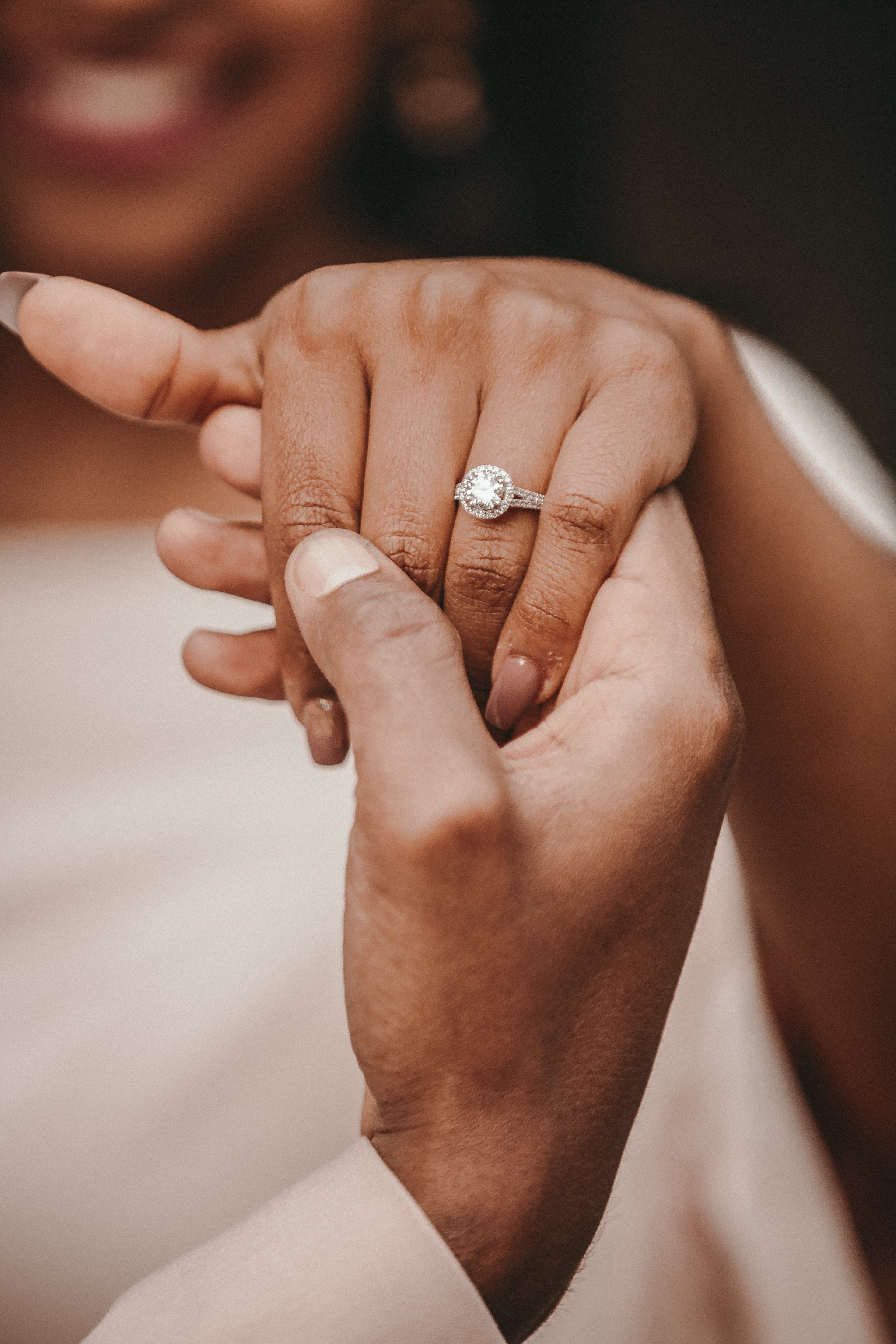 Einer Frau wird ein Verlobungsring an die Hand gesteckt.