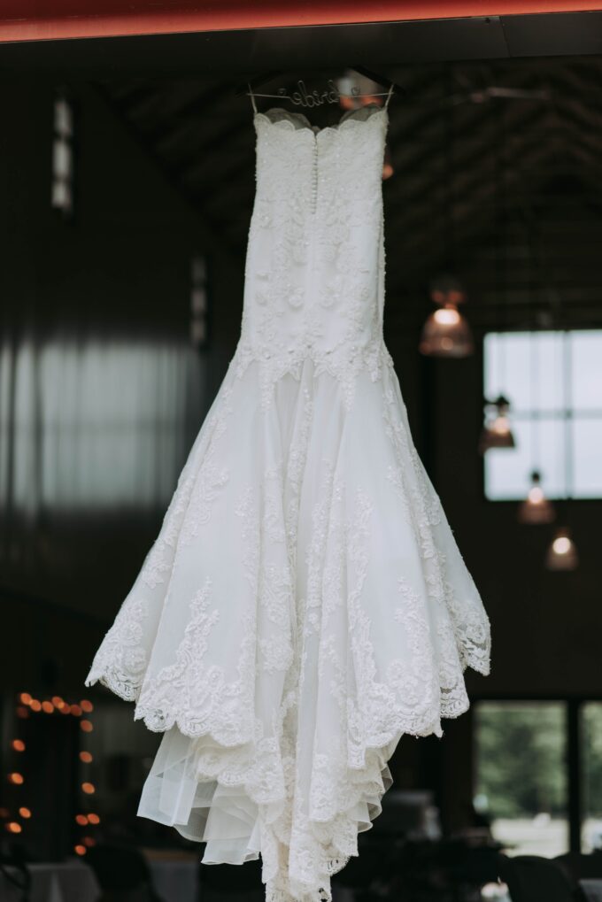 Ein Hochzeitskleid hängt auf einem Kleiderbügel in einer Scheune.
