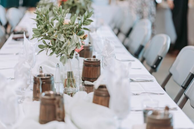 Ein langer Tisch mit Blumen und Vasen darauf.