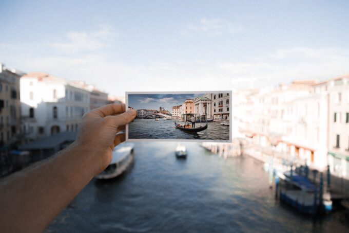 Eine Person hält ein Foto eines Bootes in Venedig hoch.