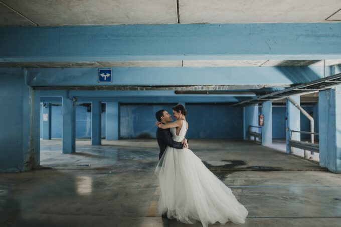 Eine Braut und ein Bräutigam umarmen sich in einem blauen Parkhaus.