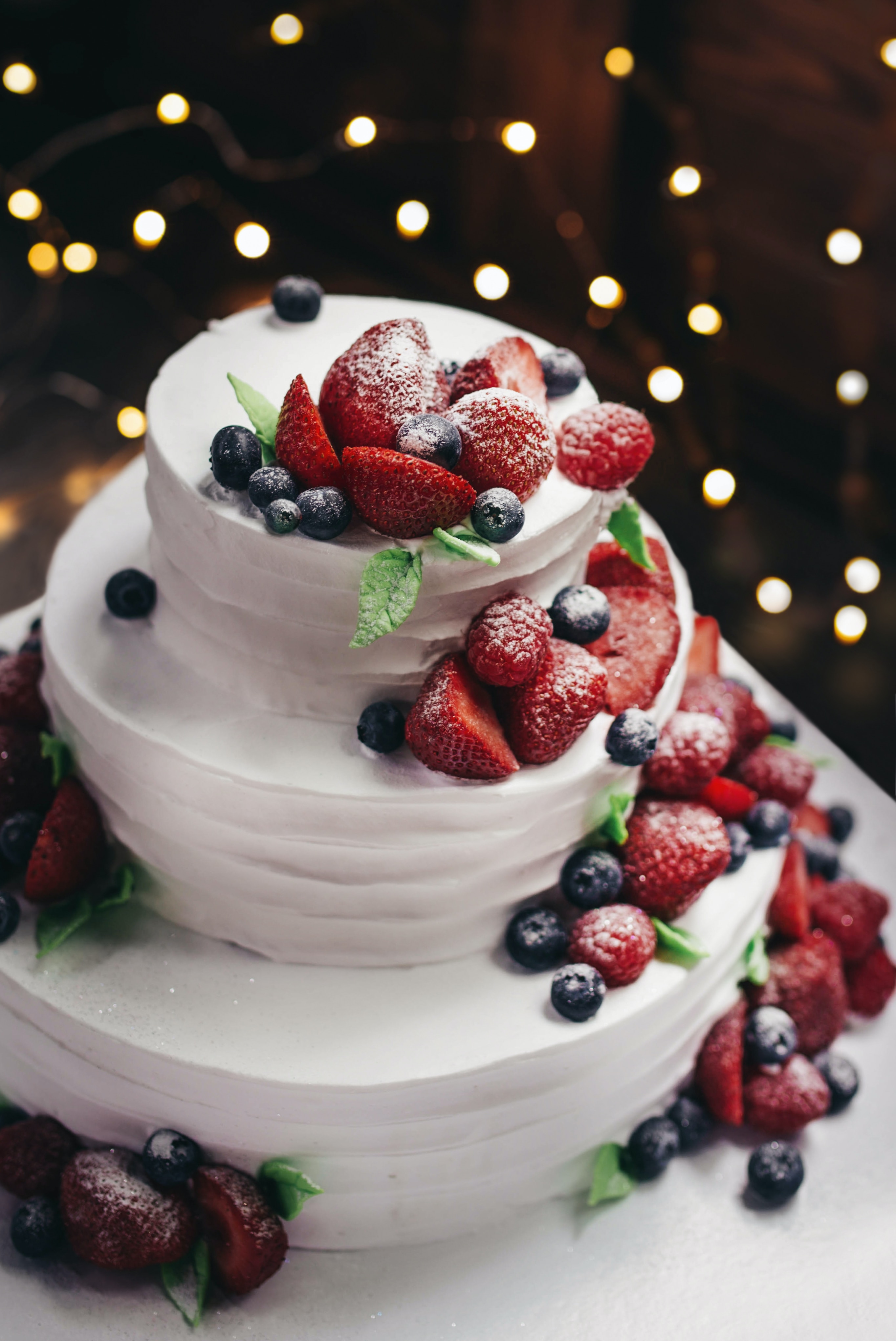 Ein weißer Kuchen mit Blaubeeren und Erdbeeren obendrauf.