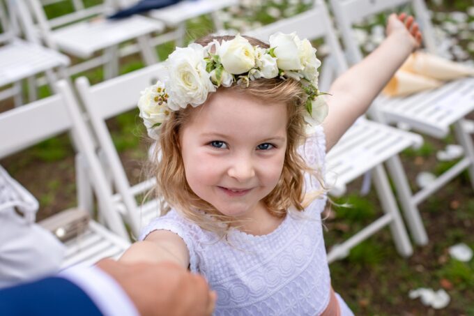 Ein kleines Mädchen, das bei einer Hochzeit eine Blumenkrone trägt.