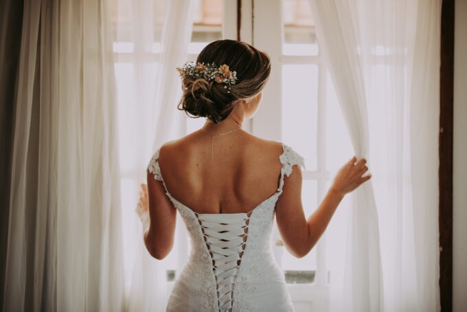 Eine Braut im Korsett schaut aus dem Fenster.