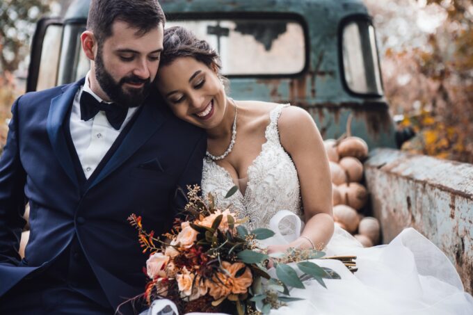 Eine Braut und ein Bräutigam sitzen auf der Ladefläche eines alten Lastwagens.