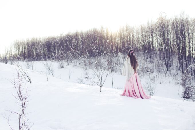 Ein Mädchen in einem rosa Kleid steht im Schnee.