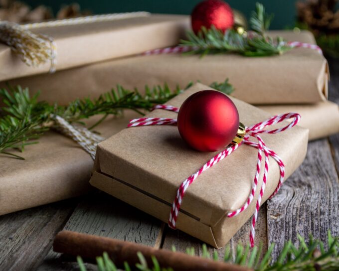 Weihnachtsgeschenke in braunem Papier verpackt auf einem Holztisch.