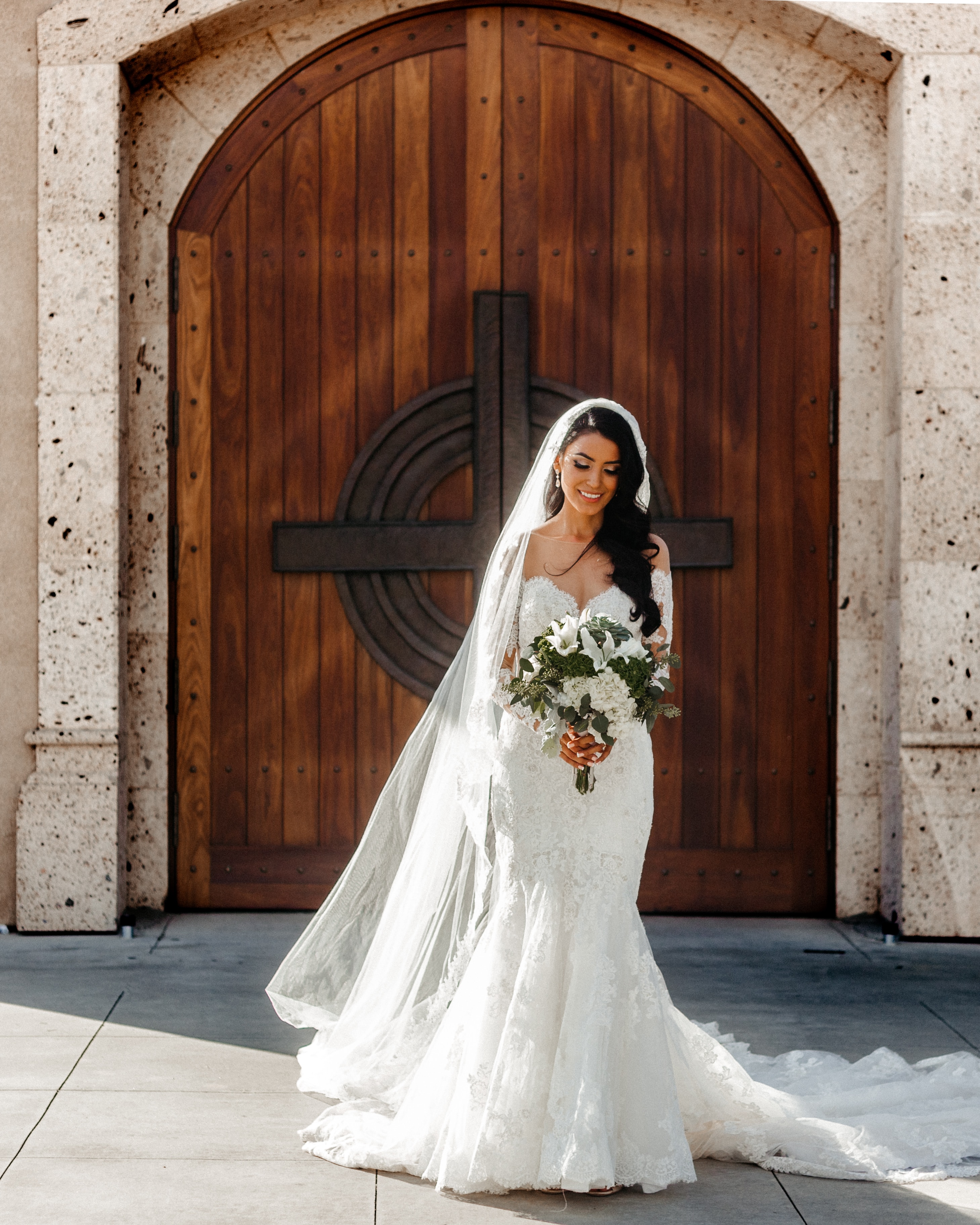 Eine Braut steht vor einer Holztür.
