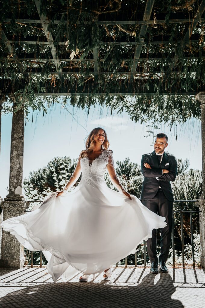 Eine Braut und ein Bräutigam posieren für ein Foto unter einer Pergola.