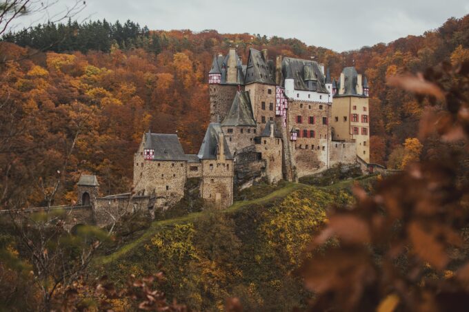 Im Herbst thront eine Burg auf einem Hügel.