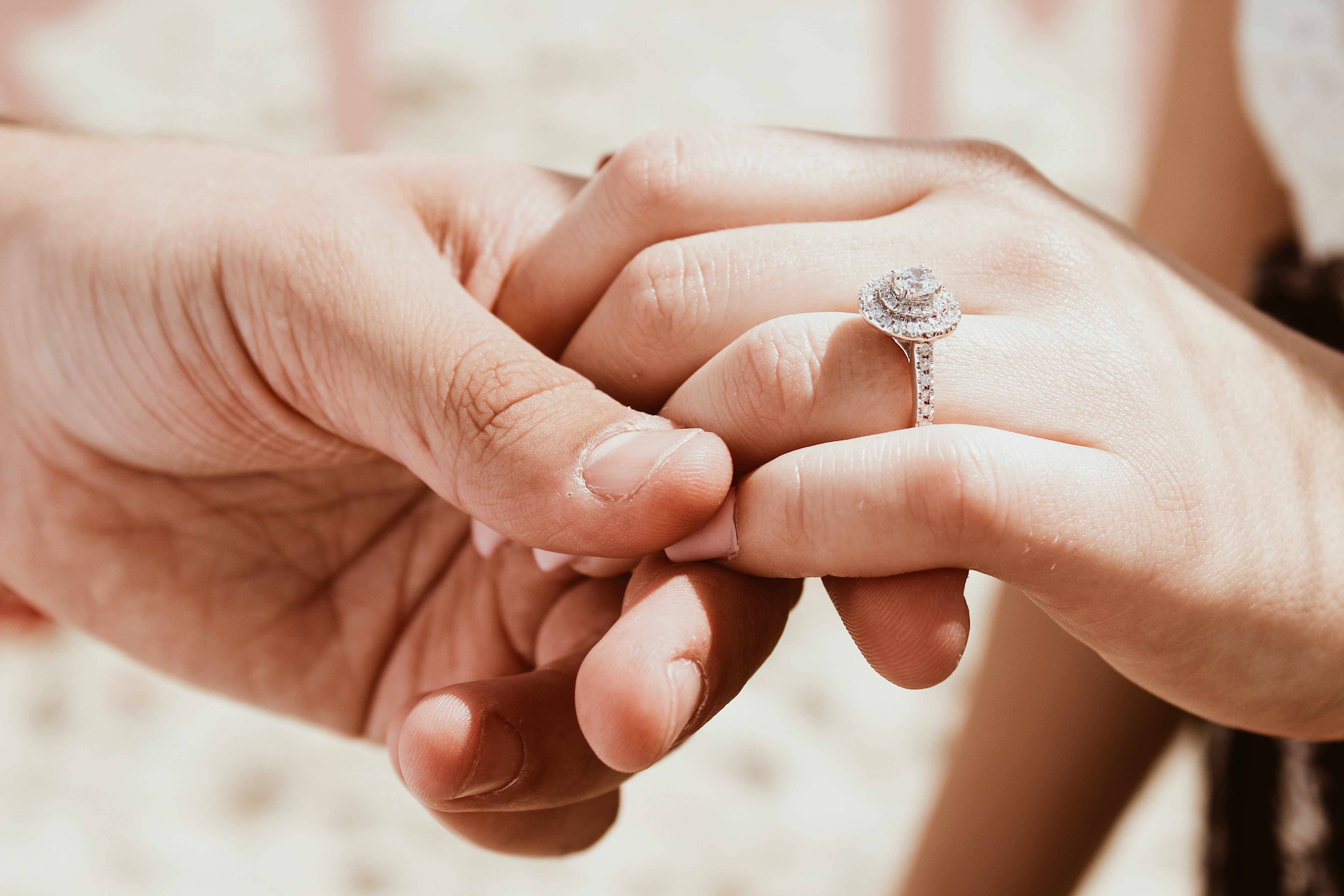 Ein Mann und eine Frau halten Händchen mit einem Verlobungsring.
