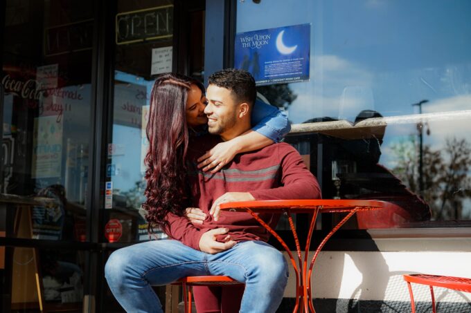 Ein Paar küsst sich vor einem Café.
