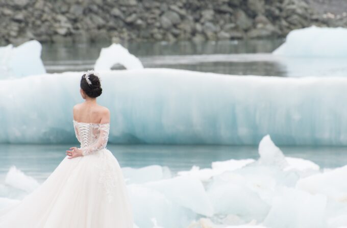 Eine Braut steht vor Eisbergen in Island.