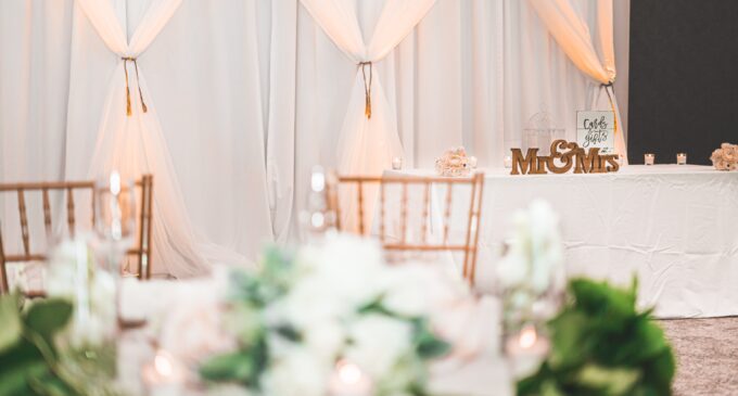 Ein Hochzeitsempfang mit weißen Vorhängen und Blumen.