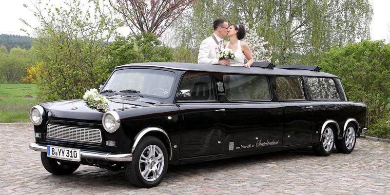 Eine Braut und ein Bräutigam posieren auf der Rückseite eines Hochzeitsautos.