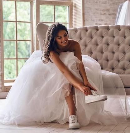 Eine Braut in einem weißen Kleid bindet ihre Schuhe.
