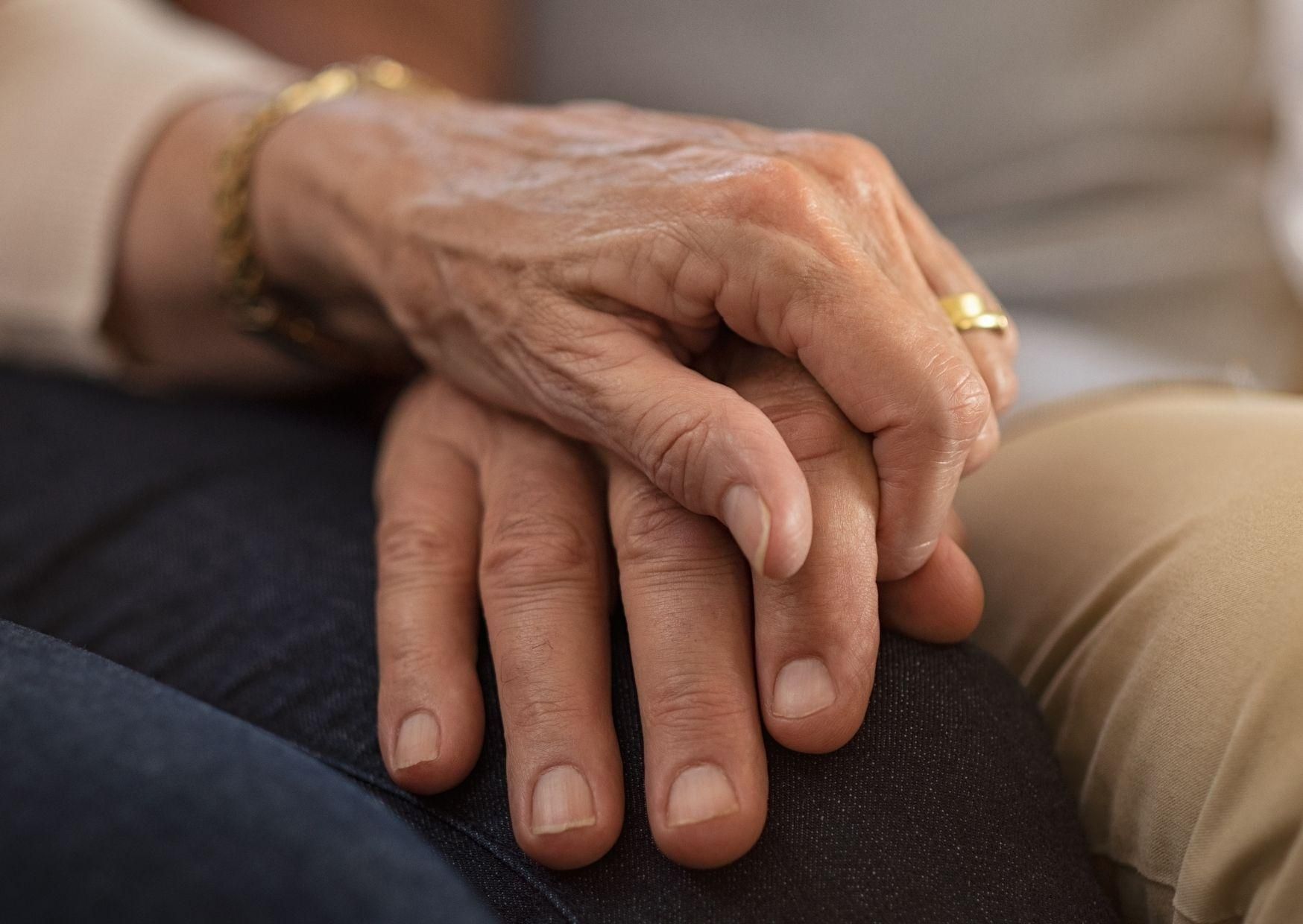 Die Hand einer Frau hält die Hand einer älteren Frau.