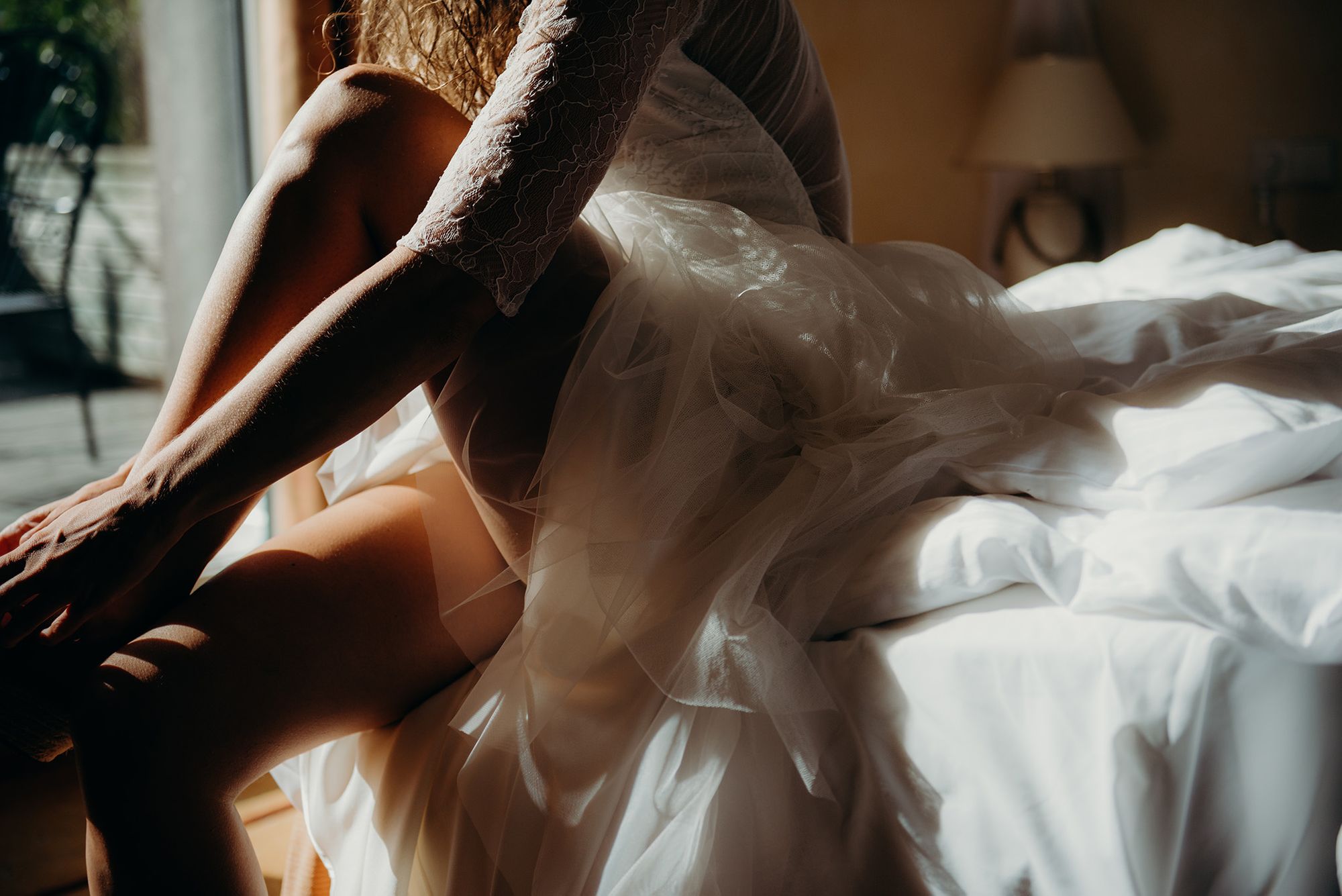Eine Braut in einem weißen Kleid sitzt auf einem Bett.