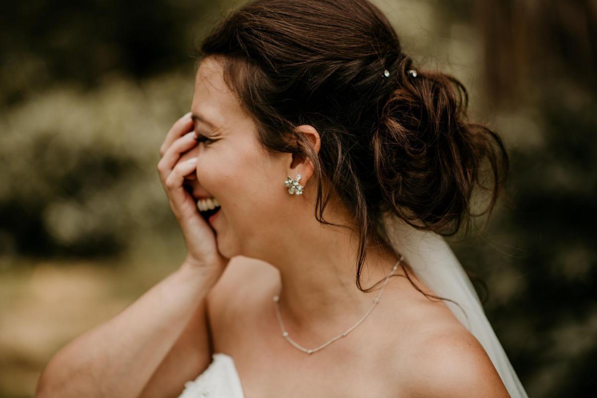 Eine Braut lacht, während sie ihren Ehering hält.