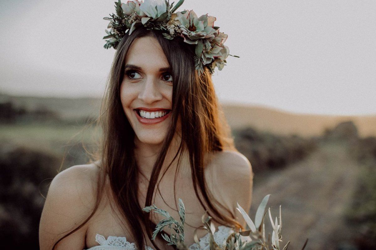 Eine wunderschöne Braut, die eine Blumenkrone auf einem Feld trägt.