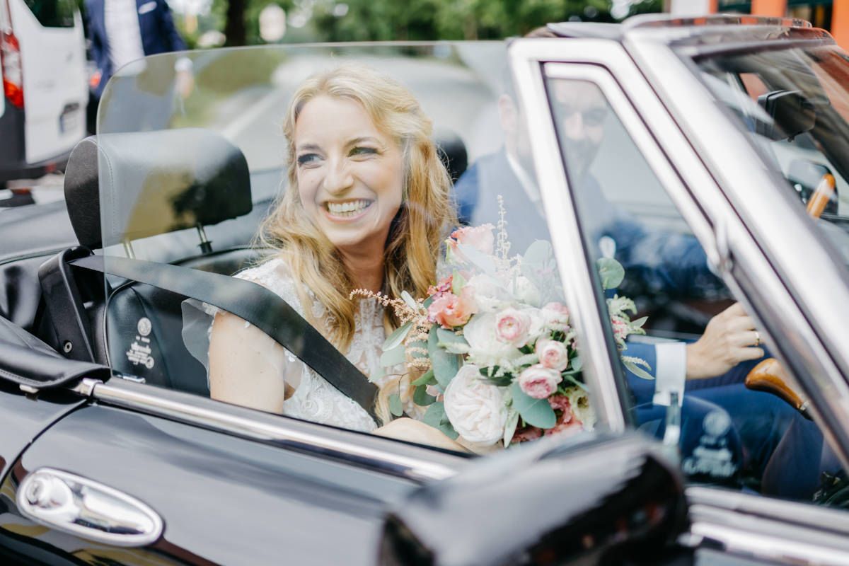 Eine Braut in einem Cabrio-Hochzeitsauto.
