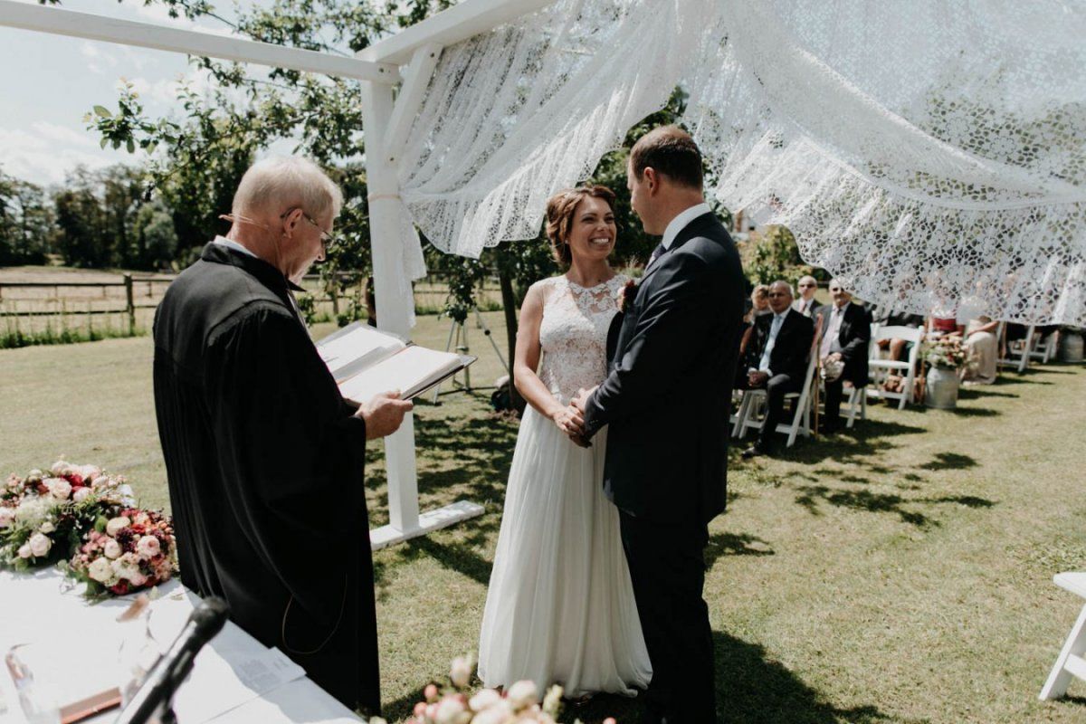 Eine Braut und ein Bräutigam geben sich unter einem weißen Baldachin das Ja-Wort.