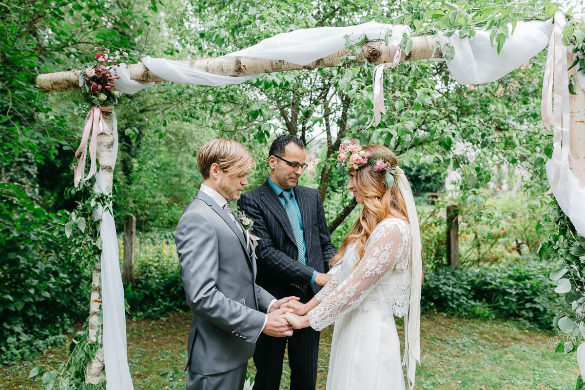 Eine Braut und ein Bräutigam geben sich in einem Garten das Ja-Wort.