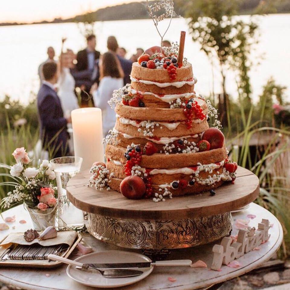 Eine dreistöckige Hochzeitstorte mit Beeren obendrauf.