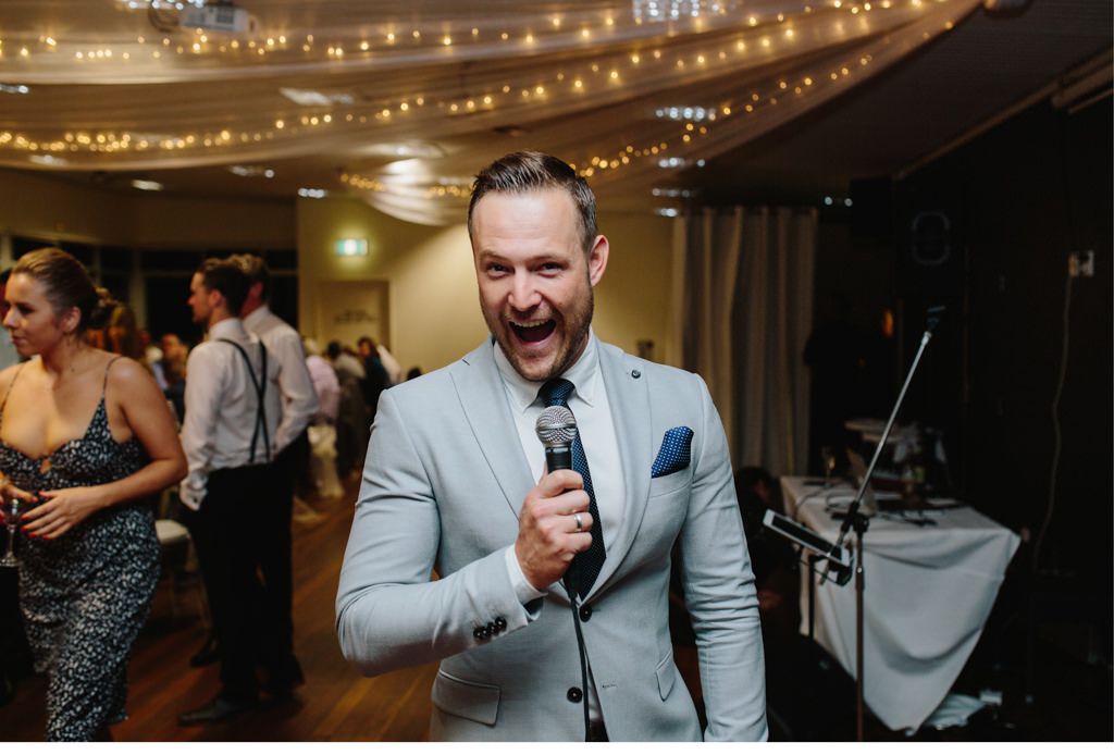 Ein Mann singt bei einer Hochzeitsfeier in ein Mikrofon.