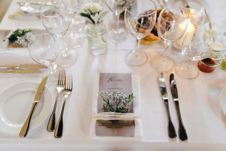 Ein weißer Tisch mit Besteck und Blumen.