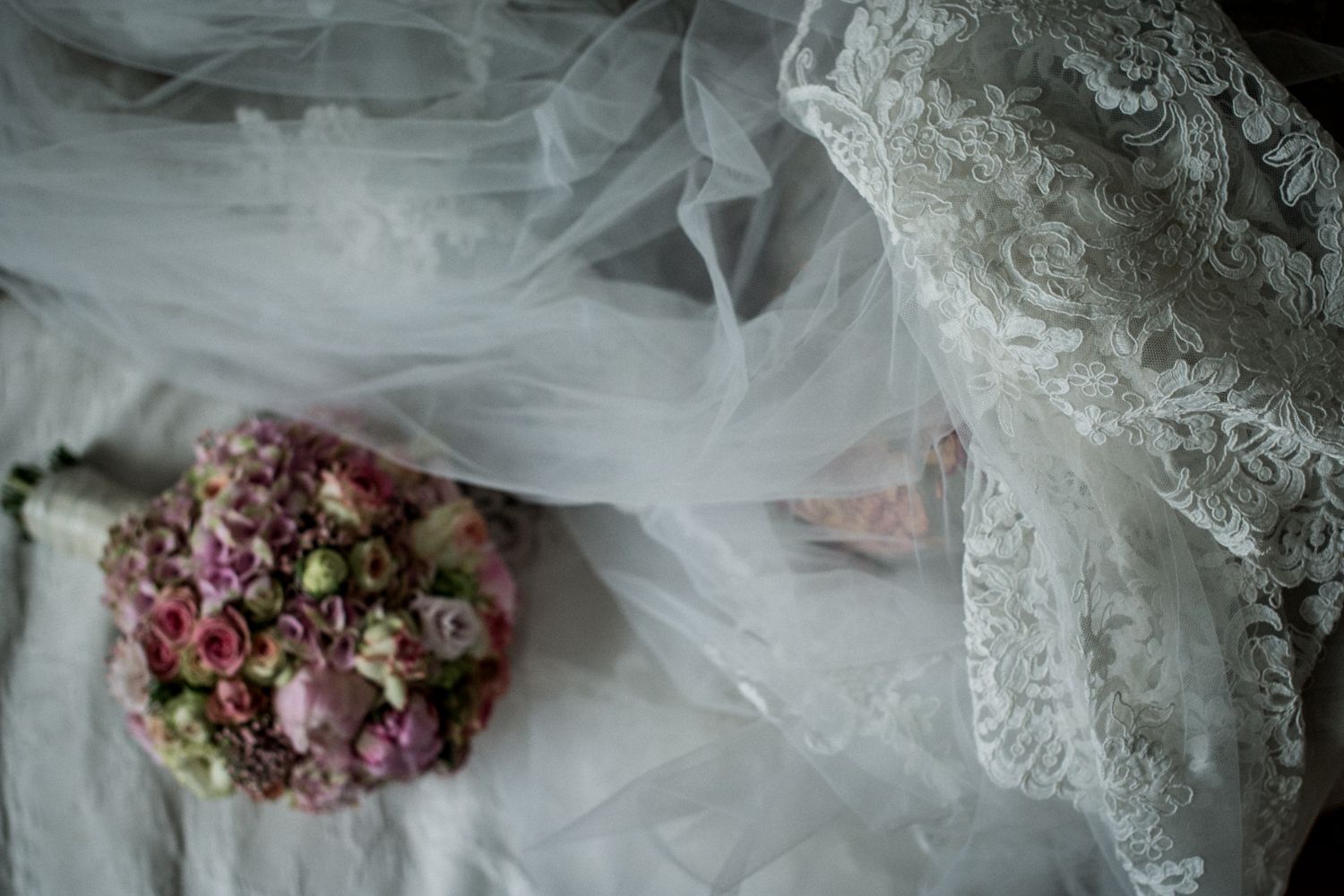 Eine Braut liegt mit einem Blumenstrauß auf einem Bett.