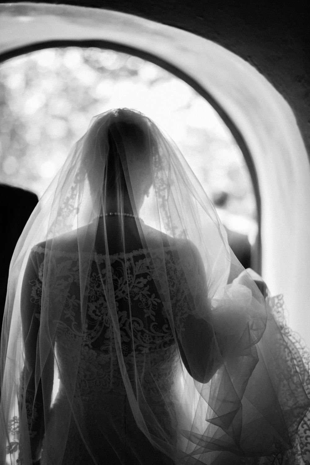 Eine Braut steht mit ihrem Schleier in einem Torbogen.