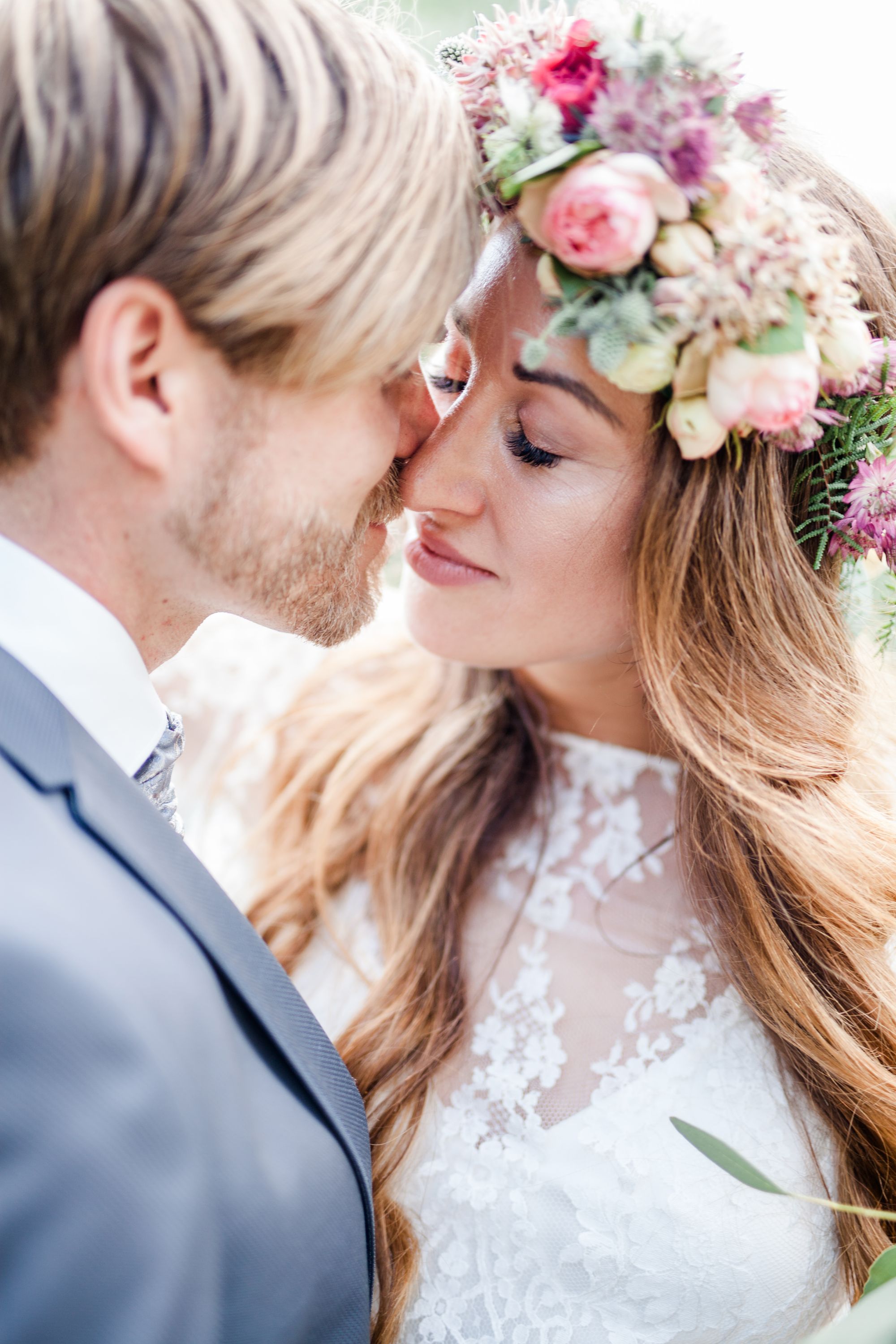 Eine Braut und ein Bräutigam küssen sich vor einer Blumenkrone.