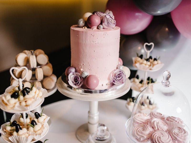 Sweet Table mit rosafarbener Torte, Macarons und Cupcakes